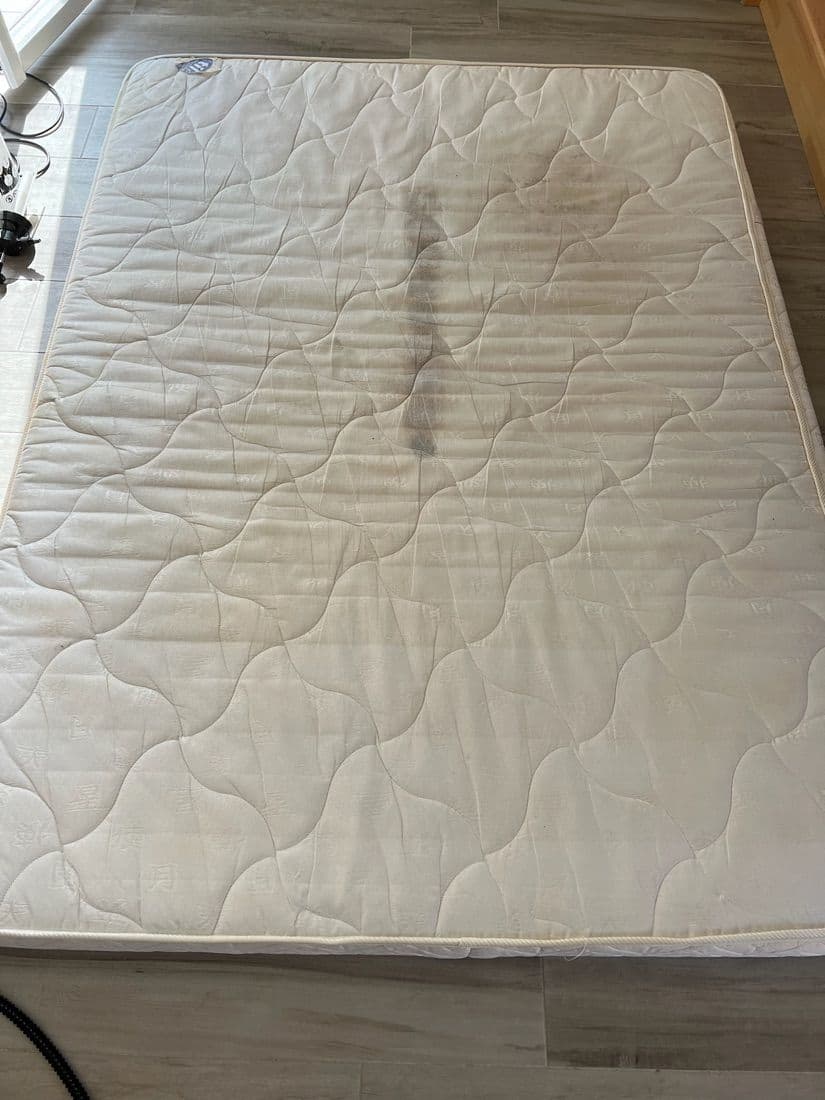 Matelas blanc avec une grande tache sombre avant nettoyage, puis propre après — avant